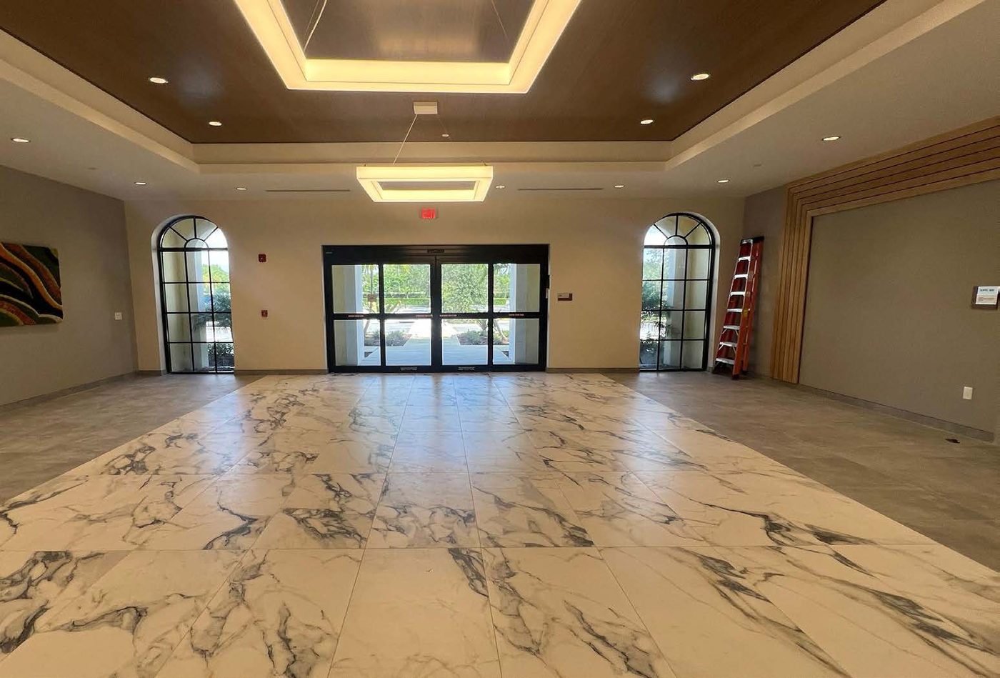 The Wellington Collegiate Academy lobby — a bright marble-floored entrance with arched windows and glass doors