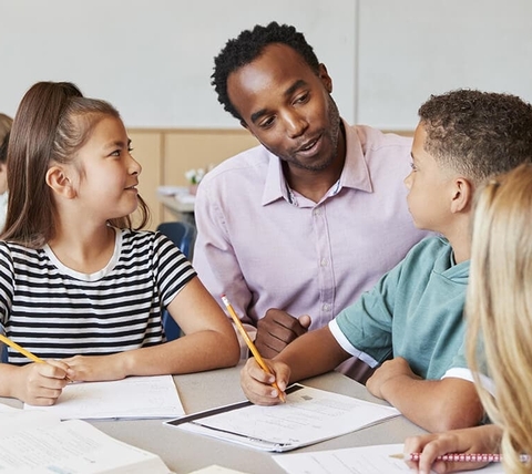A teacher working with a small group of students at a classroom table