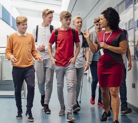 Students walking and talking with a teacher in a school hallway
